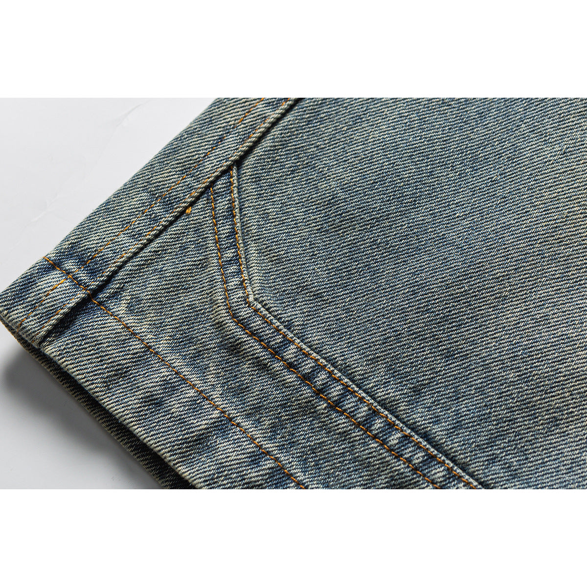 Close-up of blue denim shorts showing a stitched leg hem and faded denim texture.