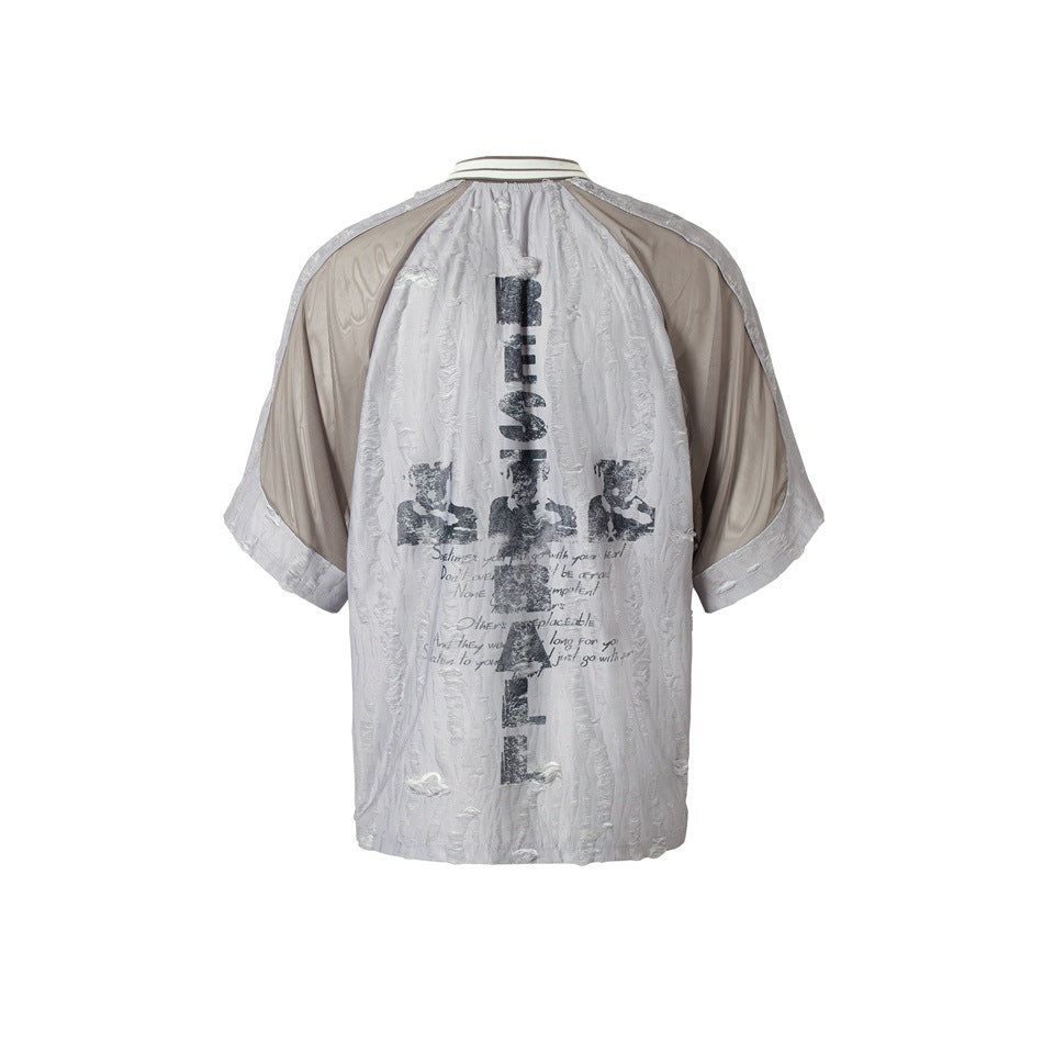 Back view of a pale gray textured shirt with taupe shoulder and sleeve panels and a large dark graphic.
