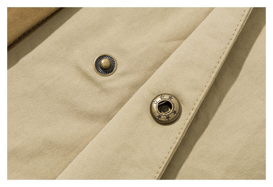 Close-up of two decorative metal snap components on beige fabric with a stitched placket.