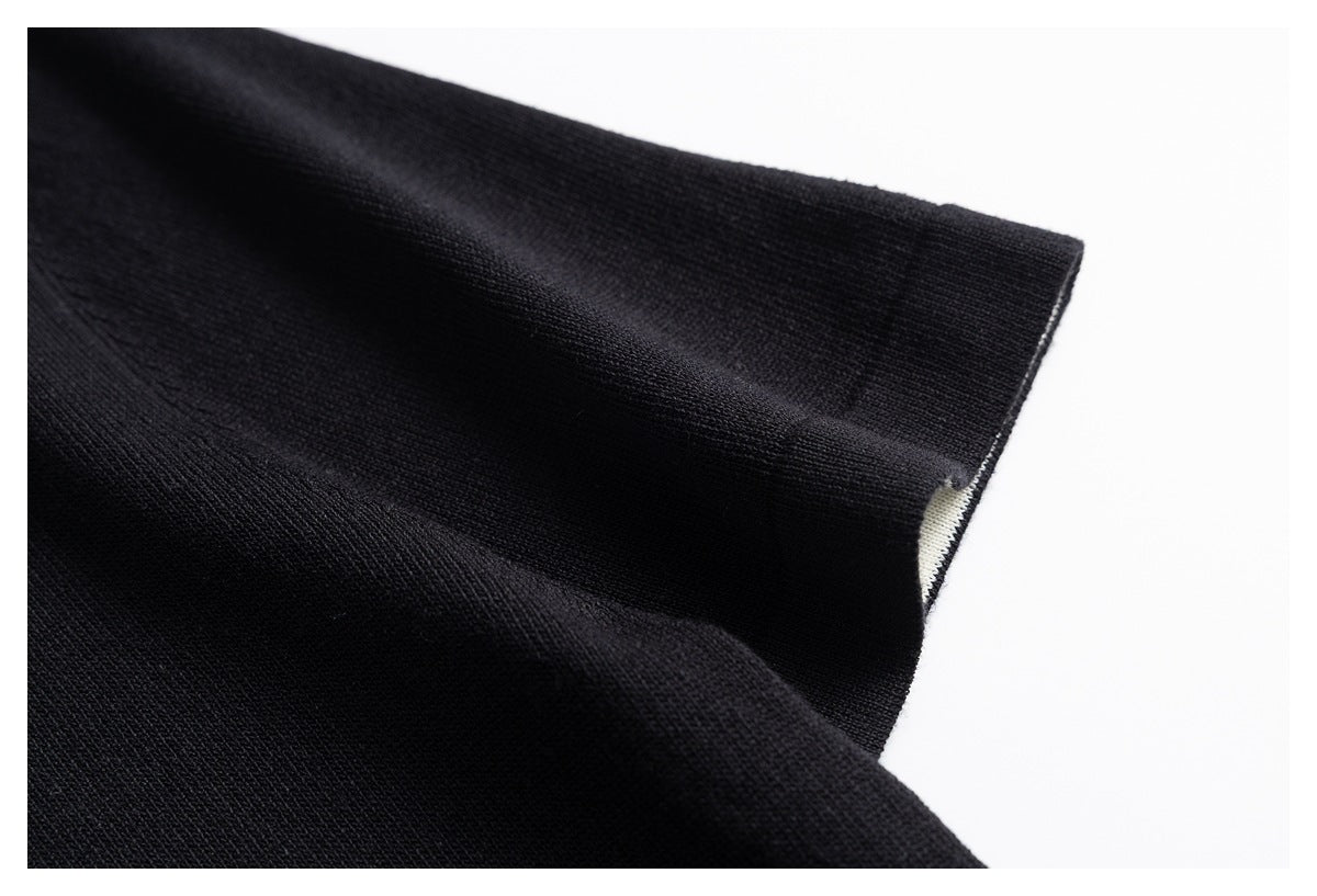 Close-up of a black knit sleeve and cuff against a white background.