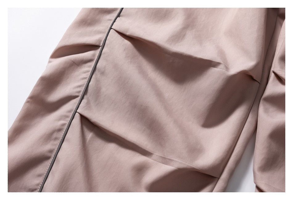 Close-up of the mauve pants' folded fabric and dark piping along a leg seam.