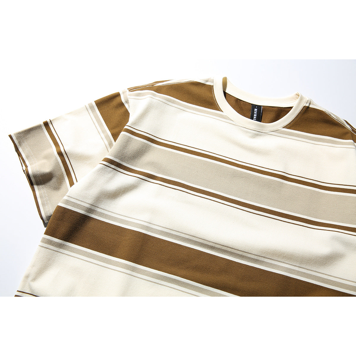 Close-up of a cream short-sleeve crew-neck T-shirt with broad brown and taupe horizontal stripes.