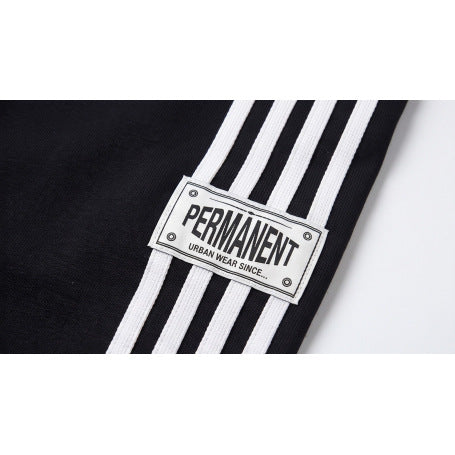 Close-up of a white PERMANENT patch across the white stripes on black pants.