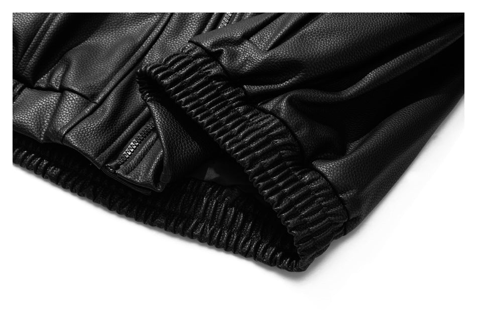 Close-up of a black pebbled jacket showing a gathered cuff, elastic hem, and zipper pocket.