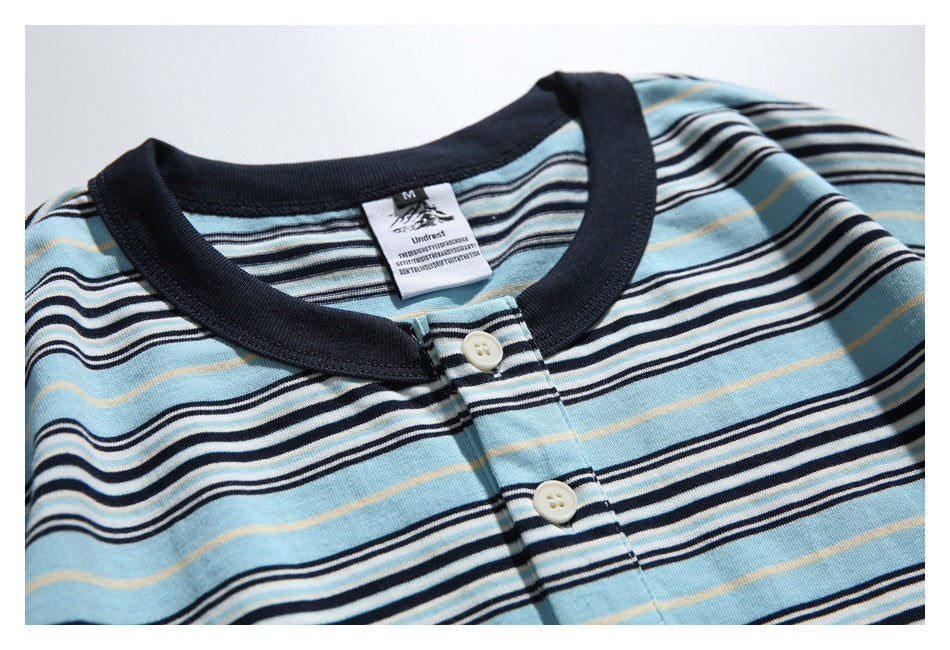 Close-up of the striped shirt's dark ribbed collar, sewn-in neck label, and two cream placket buttons.