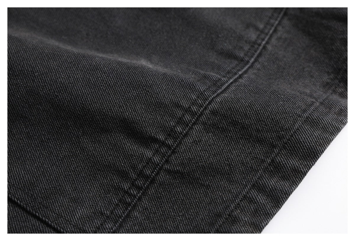 Close-up of black denim showing stitched seams and a folded edge.