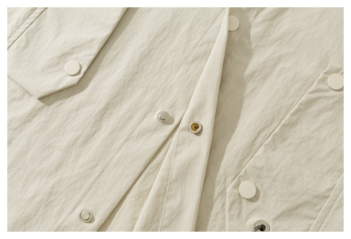 Close-up showing the ivory shirt-jacket's front snap fasteners, placket, and pocket flap.