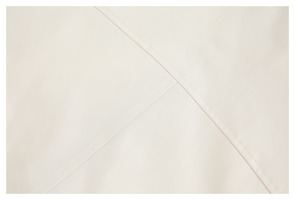 Close-up of ivory fabric showing intersecting stitched seams.