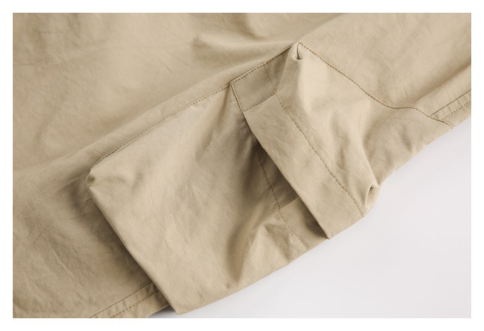 Close-up of beige pants showing a large flap pocket and its stitched construction.