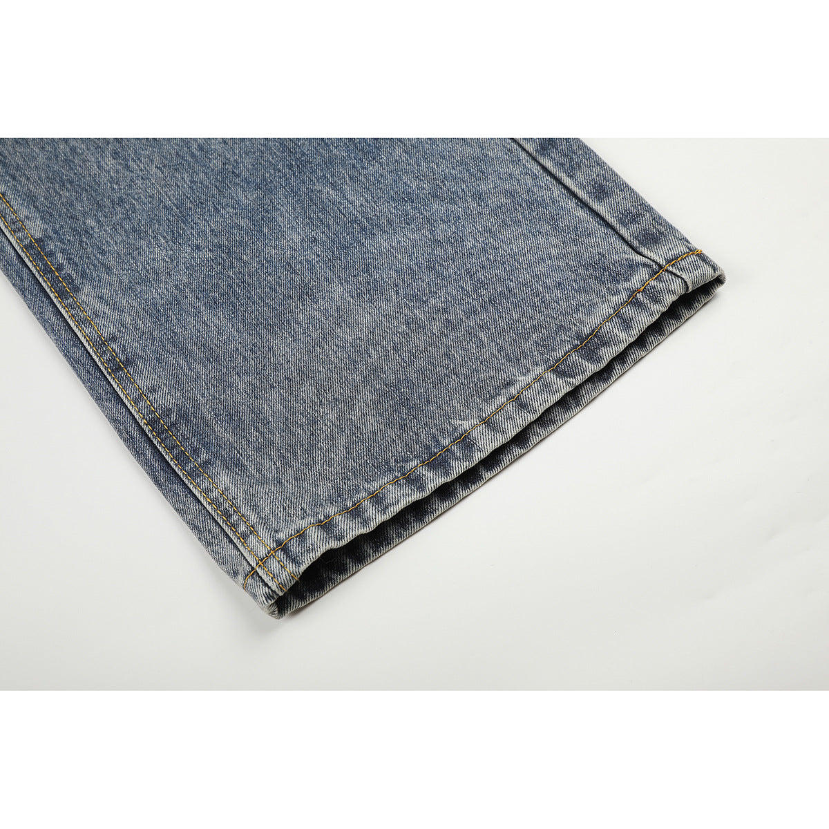 Close-up of the hem and stitching on a wide leg of blue acid-wash jeans.