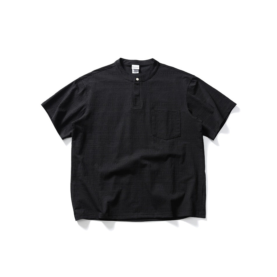 Black short-sleeve Henley-style top with band collar, snap placket, chest pocket and textured pattern, flat lay