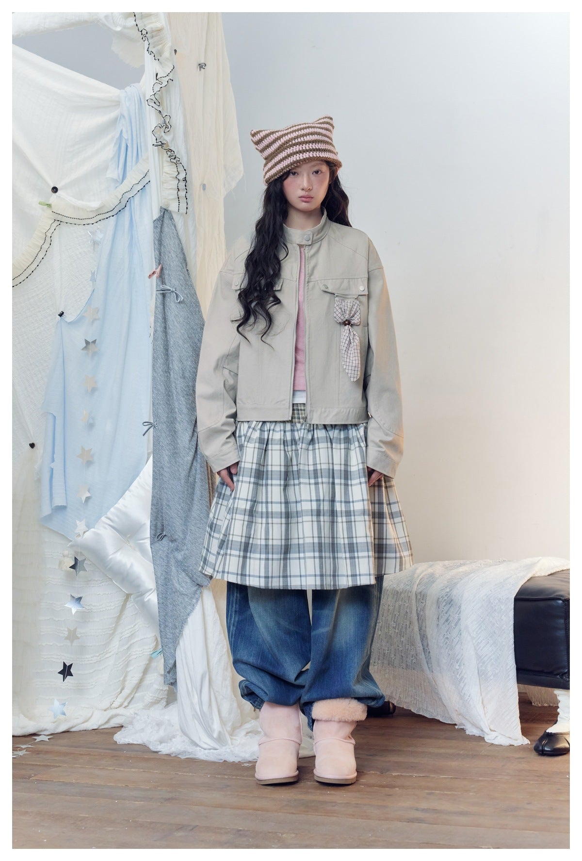 Model wearing the grey cropped zip jacket with a plaid skirt, wide-leg jeans, striped knit hat and pink boots
