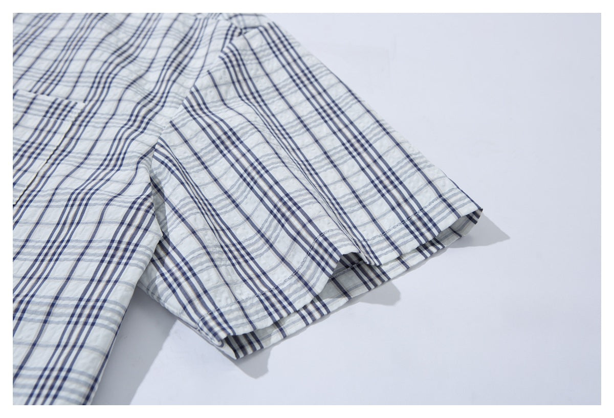 Close-up of the short sleeve and hem on a white shirt with navy and gray plaid.