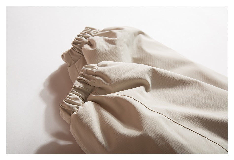 Beige jacket sleeves laid flat, showing gathered elastic cuffs and a seam.