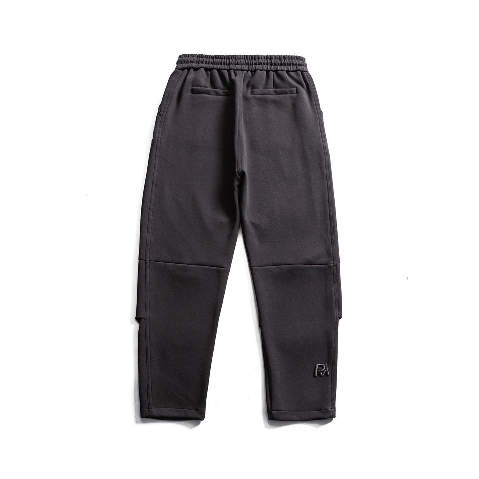 Back view of charcoal tapered pants with an elastic waistband, two welt pockets, and panel seams.