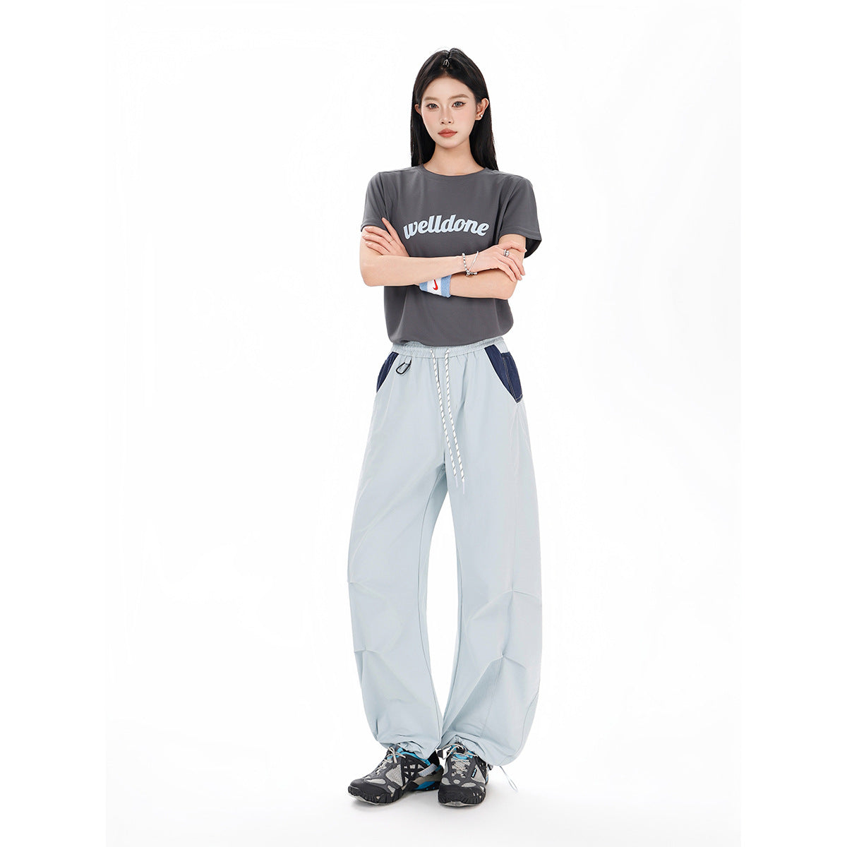 Model wearing a charcoal graphic T-shirt and pale blue wide-leg pants with navy pocket panels and a drawstring waist.
