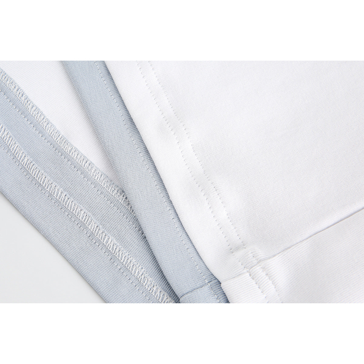 Close-up of white T-shirt seams and stitched hems with pale blue-gray fabric trim.