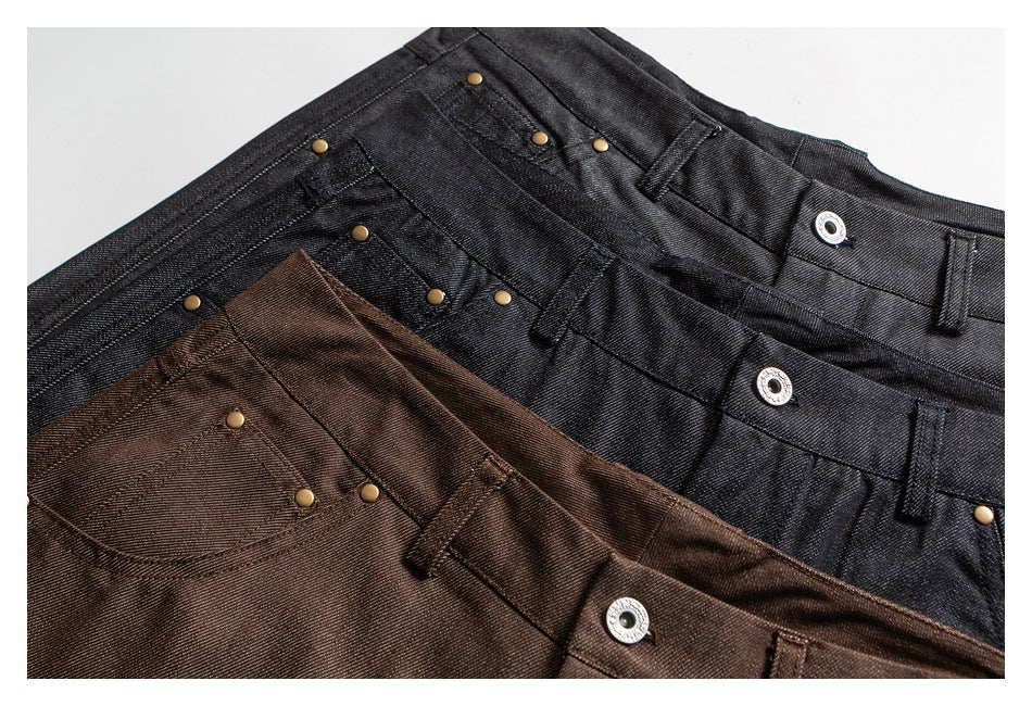Overlapping black and brown trousers shown close up, with waistbands, pockets, rivets, and metal buttons.