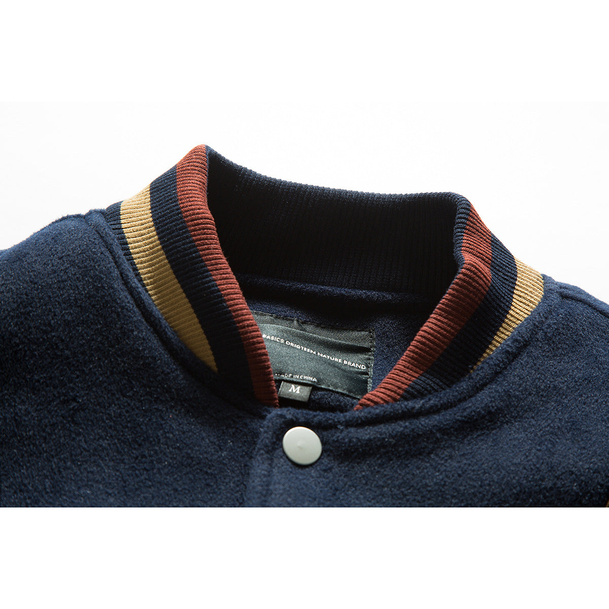 Close-up of a navy jacket collar with burgundy and gold striped ribbing, a snap, and an inner size label.