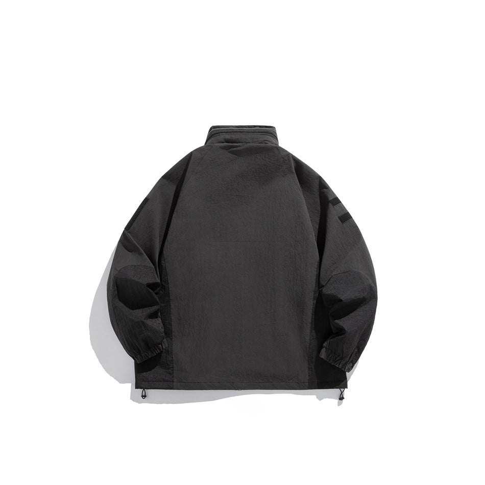 Back view of a dark charcoal hooded jacket laid flat, with long sleeves, elastic cuffs and adjustable hem toggles.