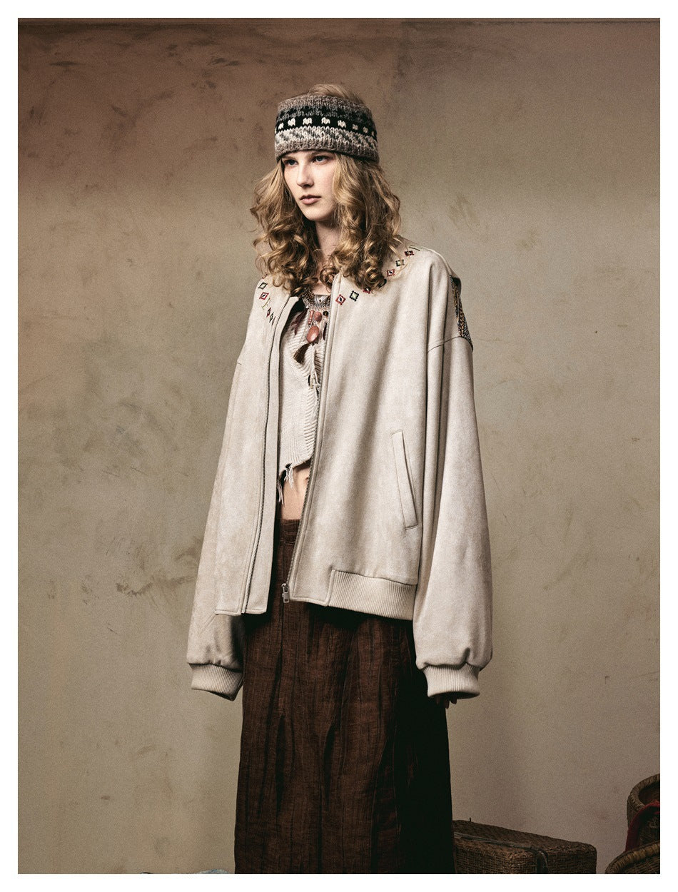 Three-quarter front view of a model wearing a cream zip jacket with colorful embroidered details and patterned sleeves.