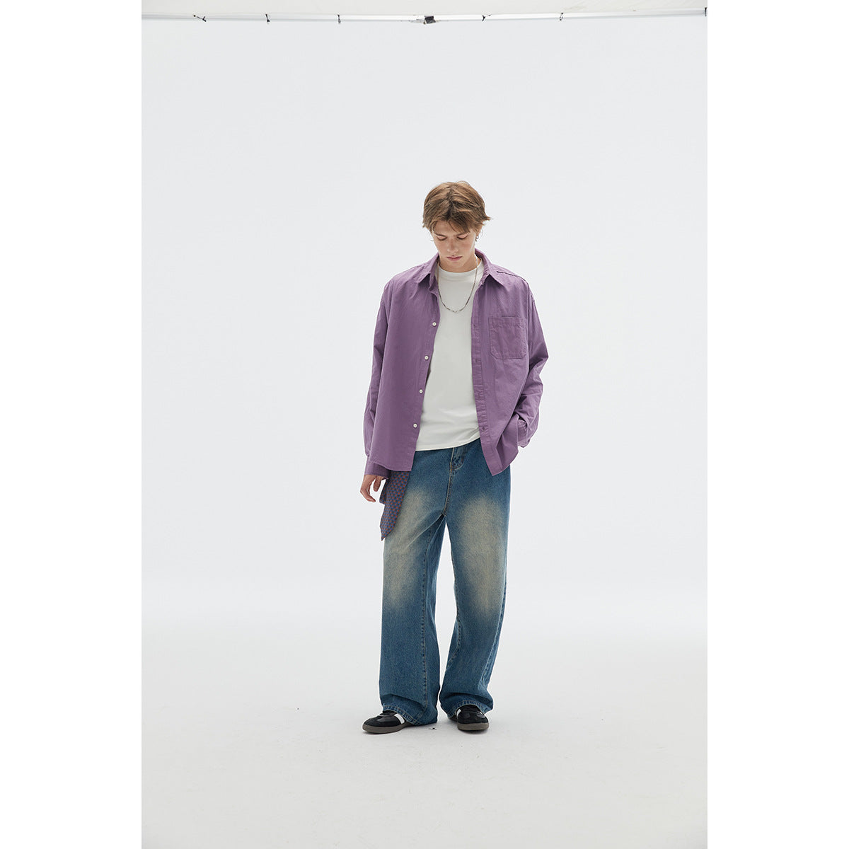 Model wearing a purple button-front shirt with a chest pocket, white tee, and loose blue jeans.