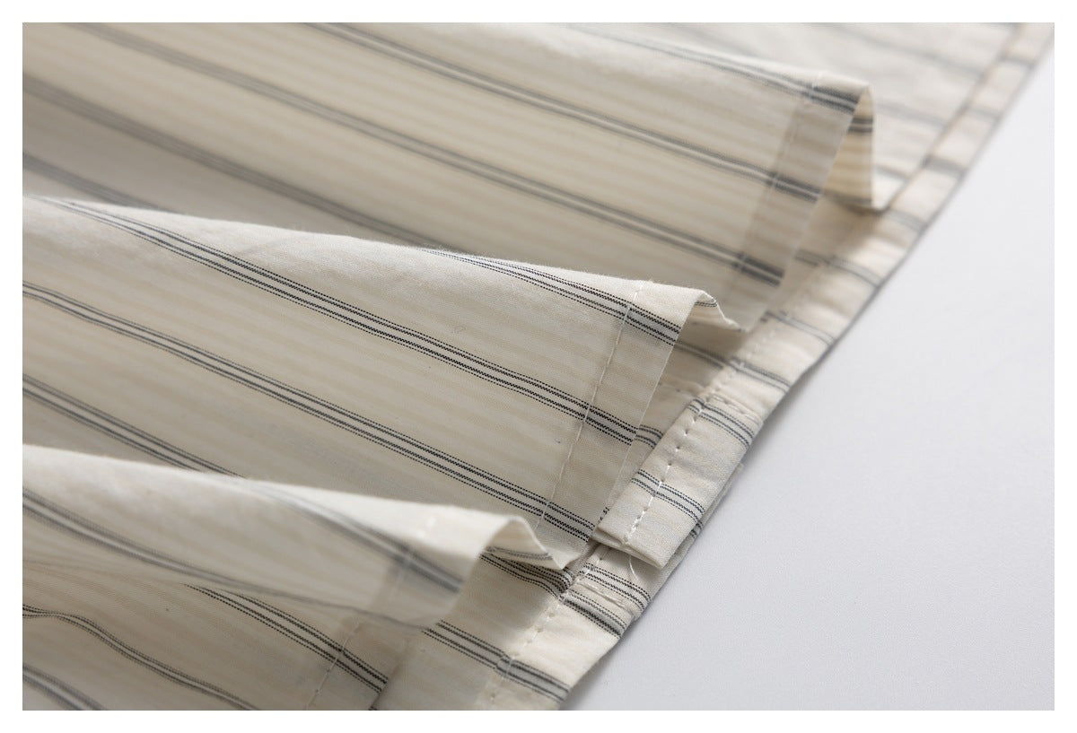 Close-up of a cream garment with thin dark stripes and a stitched folded edge.