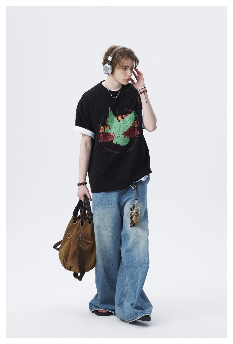 Full-length model wearing a black graphic T-shirt layered over a white tee, with loose blue jeans.