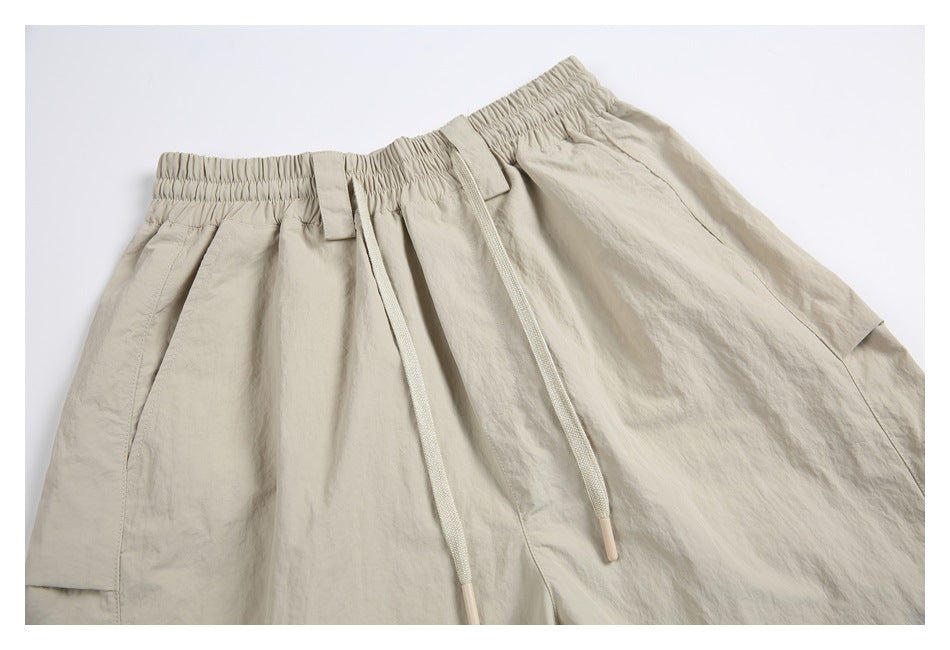 Close front view of beige cargo shorts with an elastic drawstring waist, belt loops, and a side cargo pocket.