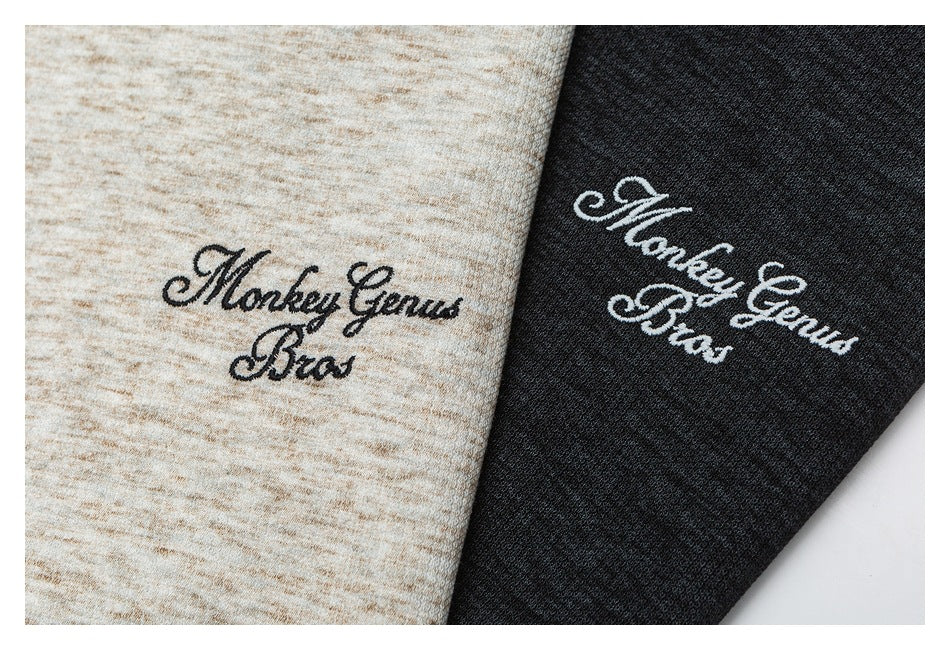 Close-up of black and white script embroidery on light beige and charcoal heather fabric.
