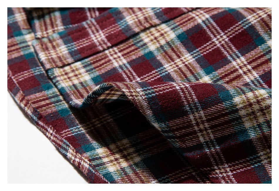 Close-up of a folded edge and seam on burgundy, teal, cream, and brown plaid shirt fabric.