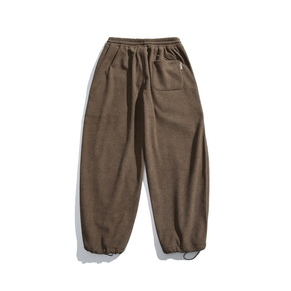 Back view of brown jogger pants with an elastic waist, a single patch pocket, and elastic cuffs.