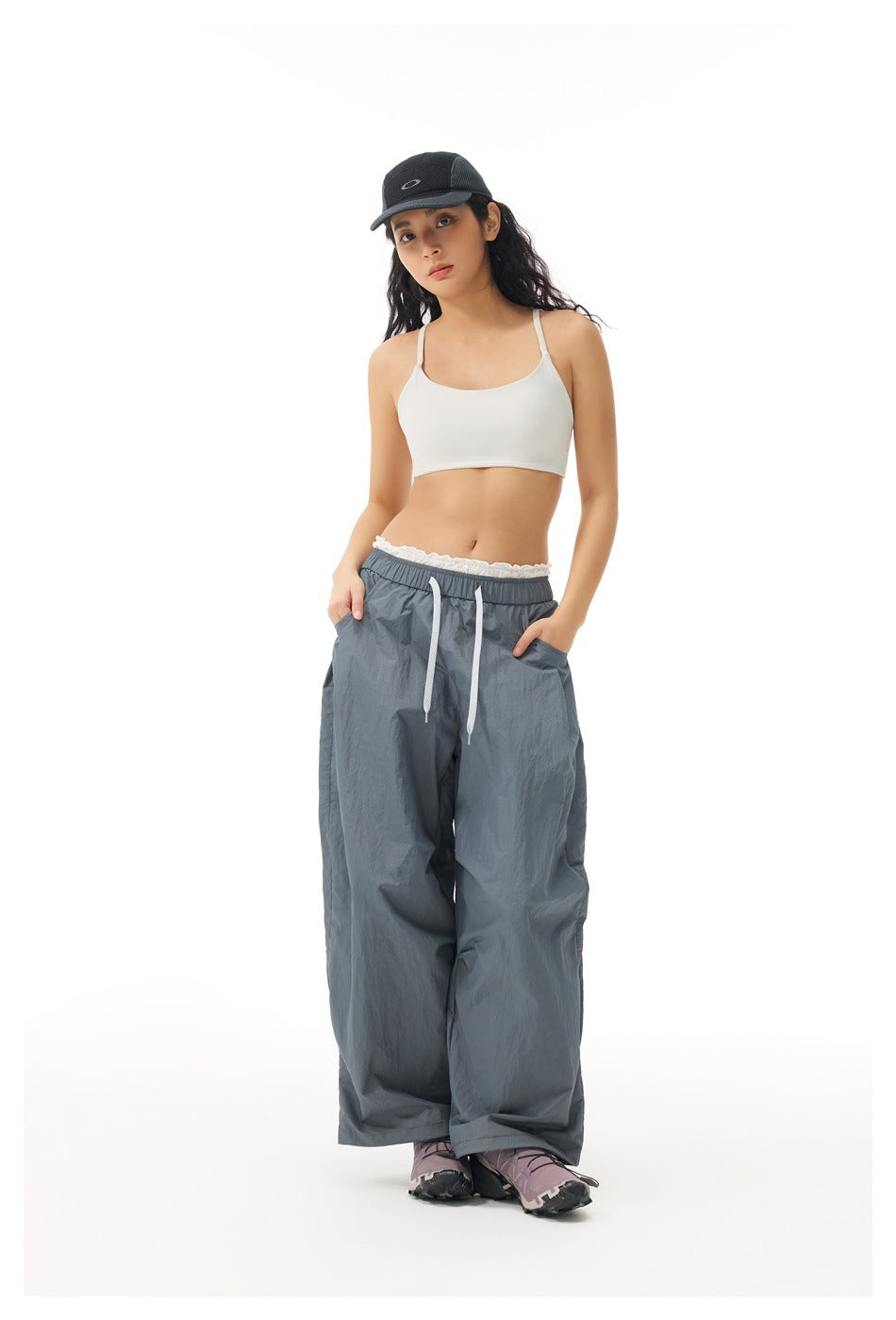 Front view of a model wearing loose slate-gray pants with white drawstrings and a lace-trim waistband.