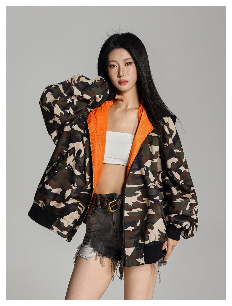 Model wearing an open camouflage jacket with bright orange lining and oversized sleeves.