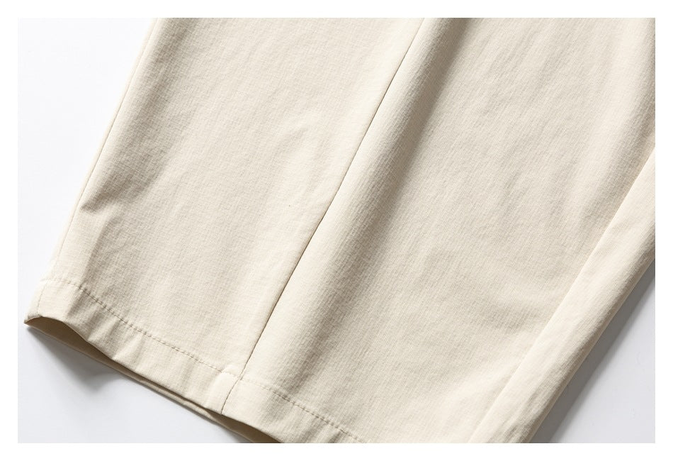 Close-up of the straight leg and stitched hem on light beige trousers.