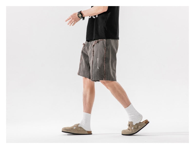 Side view of a model walking in charcoal shorts with frayed panel seams.