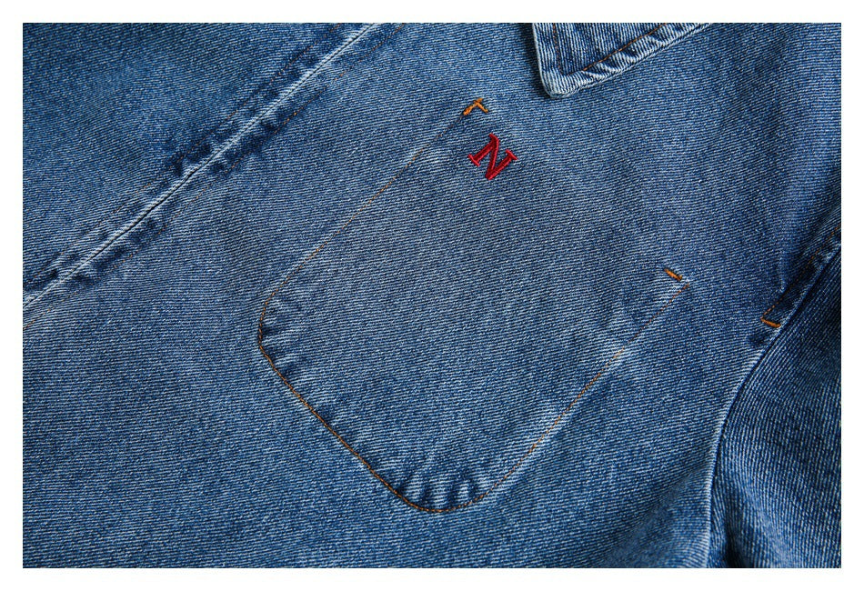 Close-up of the jacket's denim chest pocket with small red and orange embroidery.