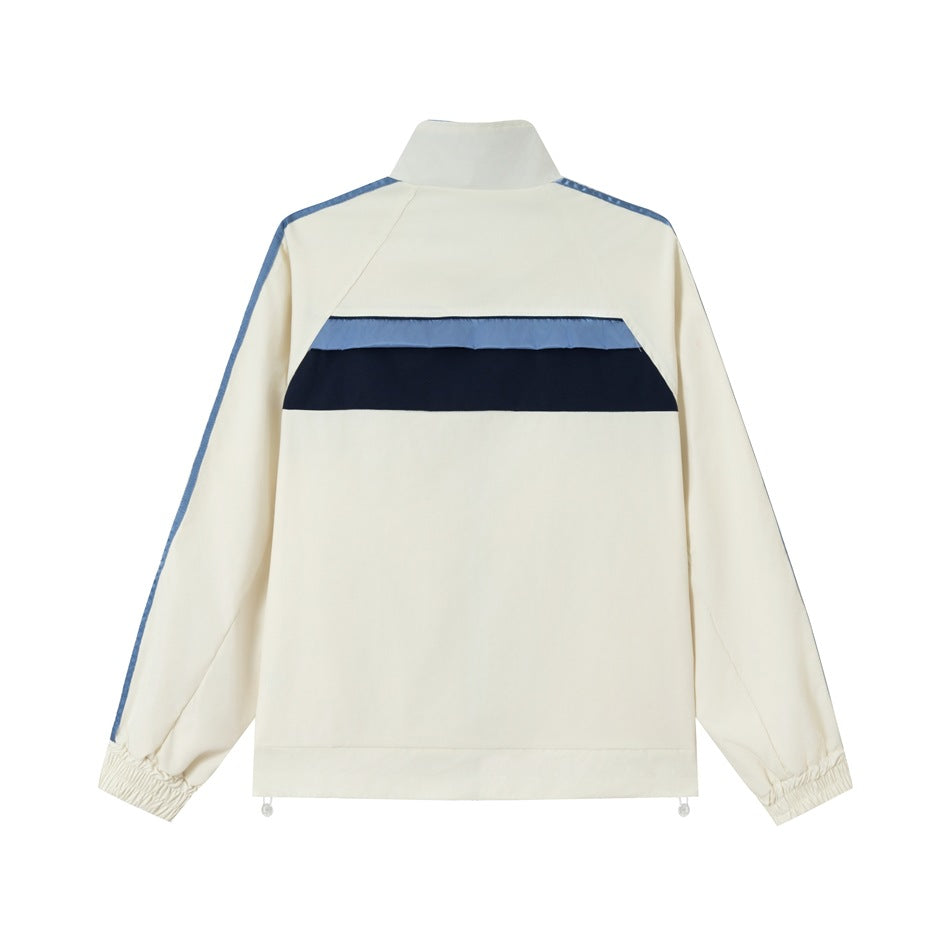 Back view of a cream track jacket with a navy and light blue horizontal stripe and blue shoulder trim.