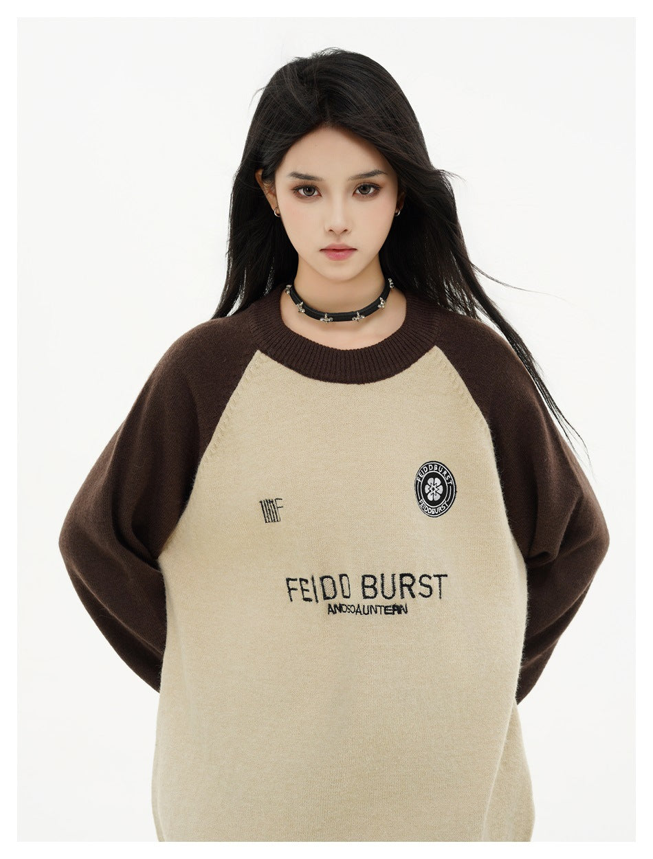 Close view of a model wearing a cream raglan sweater with dark brown sleeves and English lettering and emblems on the front.