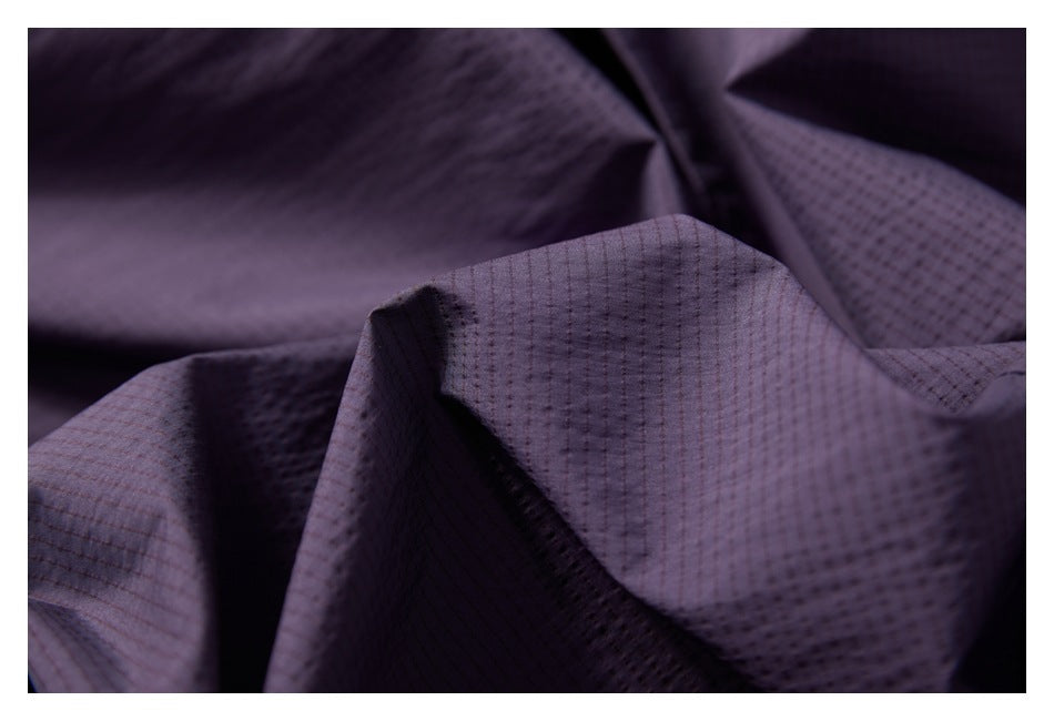Close-up of folded dark purple fabric with a fine grid pattern.