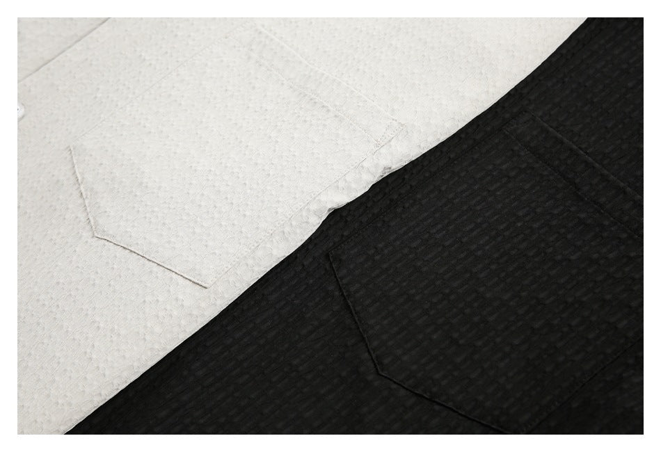Close-up of ivory and black textured shirt fabric, each with a chest pocket.
