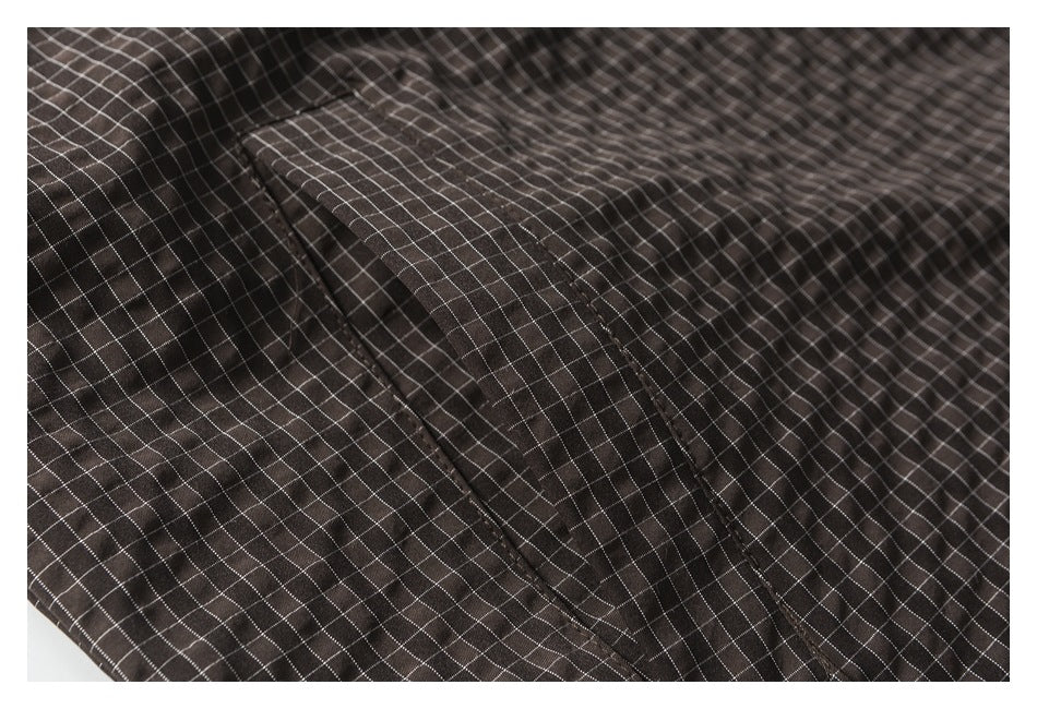 Close-up of a pocket flap on dark brown checked garment fabric.