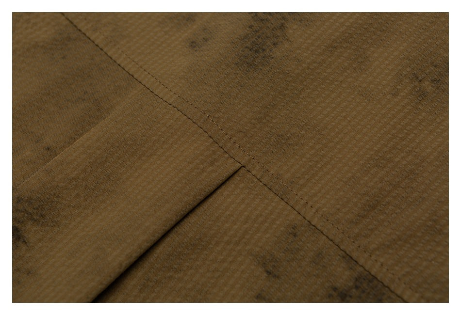 Close-up of brown mottled fabric with a diagonal stitched seam.
