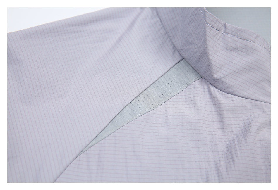 Close-up of a pale lavender jacket's shoulder seam and contrasting gray-green inset panel.