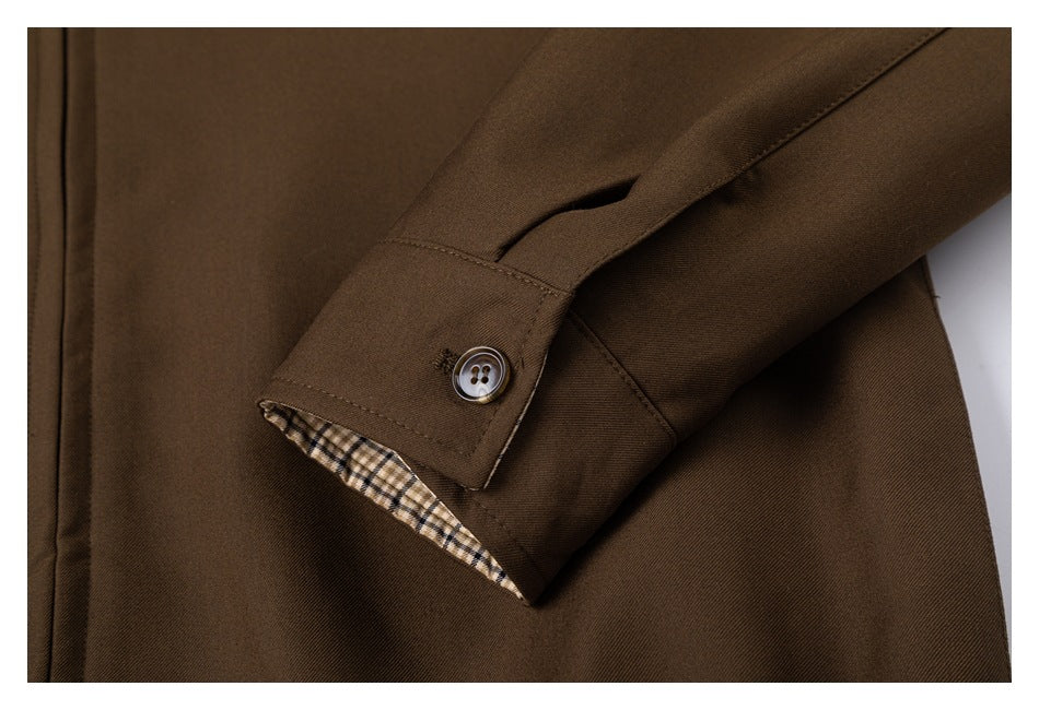 Close-up of a brown jacket sleeve cuff with a button and a glimpse of plaid lining.