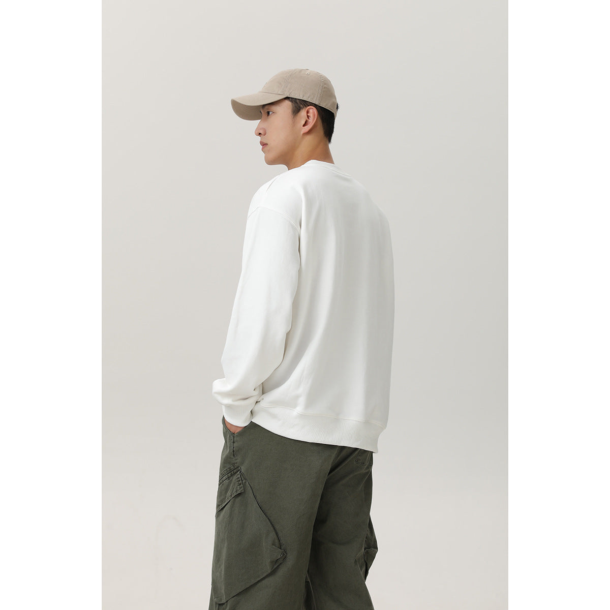 Model shown from behind wearing a plain white crewneck sweatshirt with relaxed sleeves.