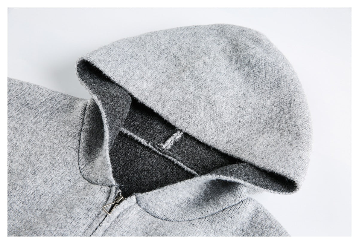 Close-up of a light gray hood with dark charcoal lining and a metal zipper pull.