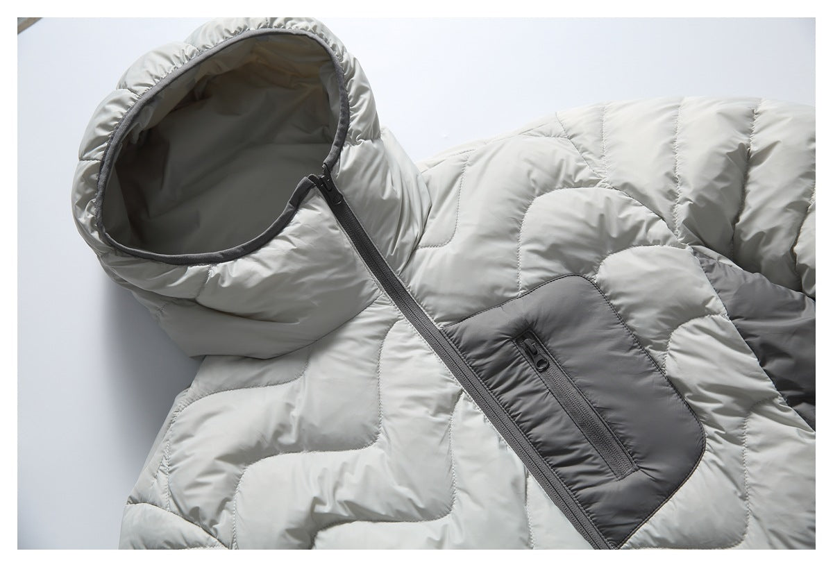 Close-up of a light gray hooded puffer jacket showing its dark-trimmed hood, diagonal zipper, and zippered chest pocket.