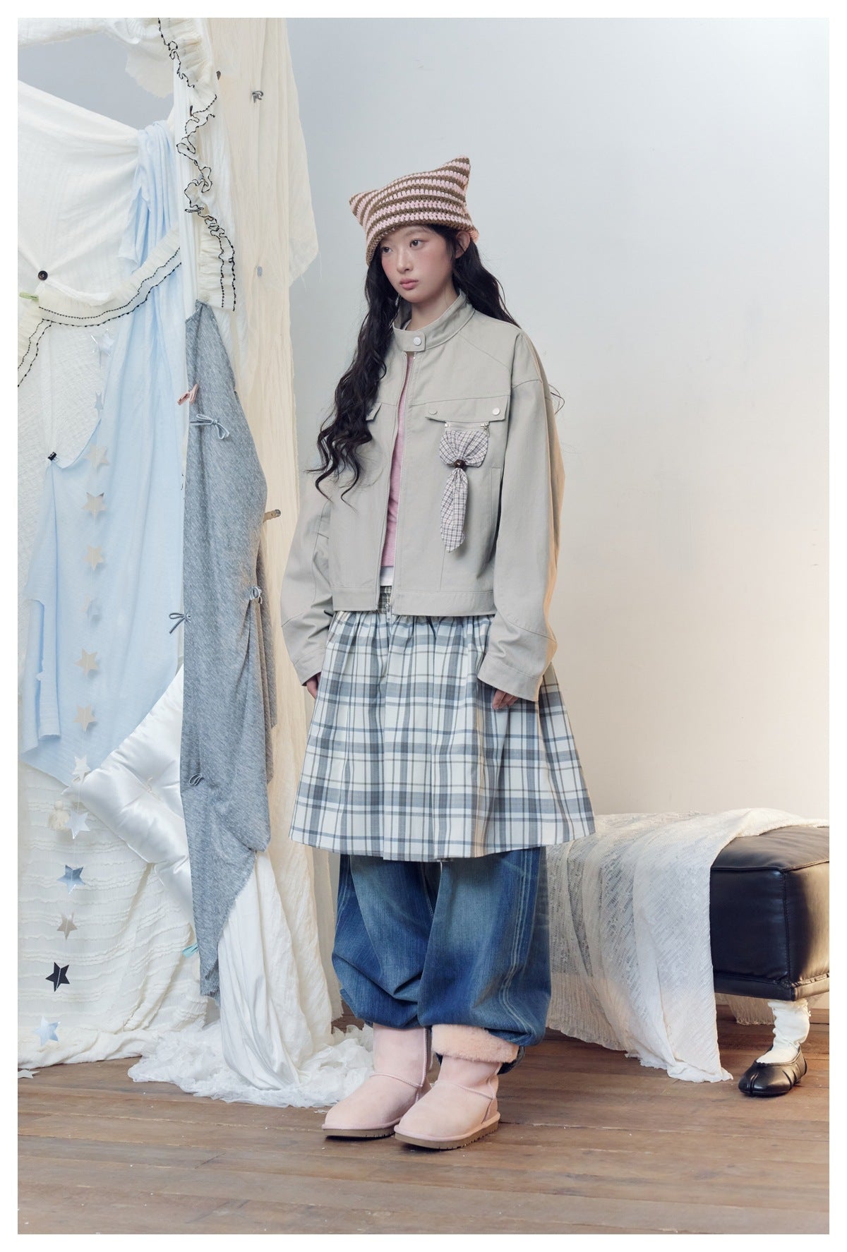 Model in the grey cropped stand-collar jacket with plaid charm, plaid skirt, jeans and pink boots, angled pose