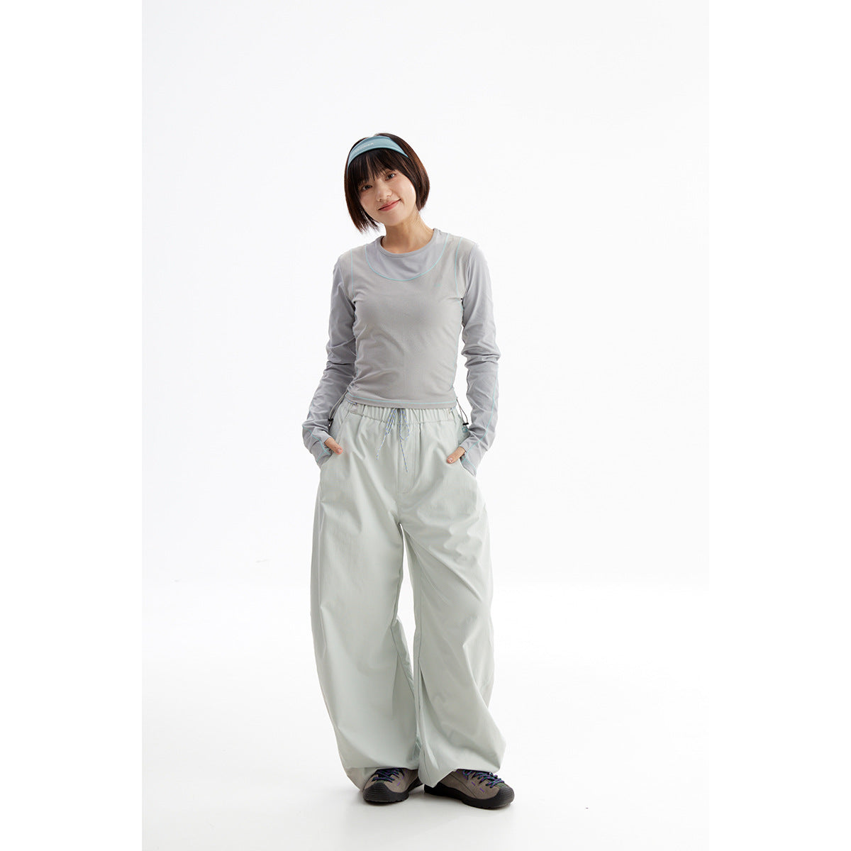 Model wearing a light gray long-sleeve top with turquoise piping and pale gray wide-leg pants.